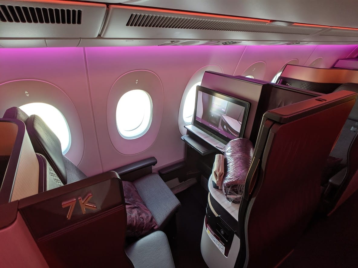 Qatar Airways Qsuite business class seat with reclining chair, television, amenity kit, and blanket