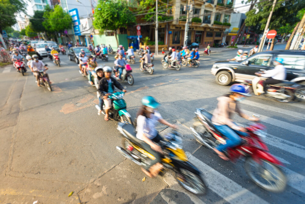 Busy daily traffic with stream of motorbikes and cars.