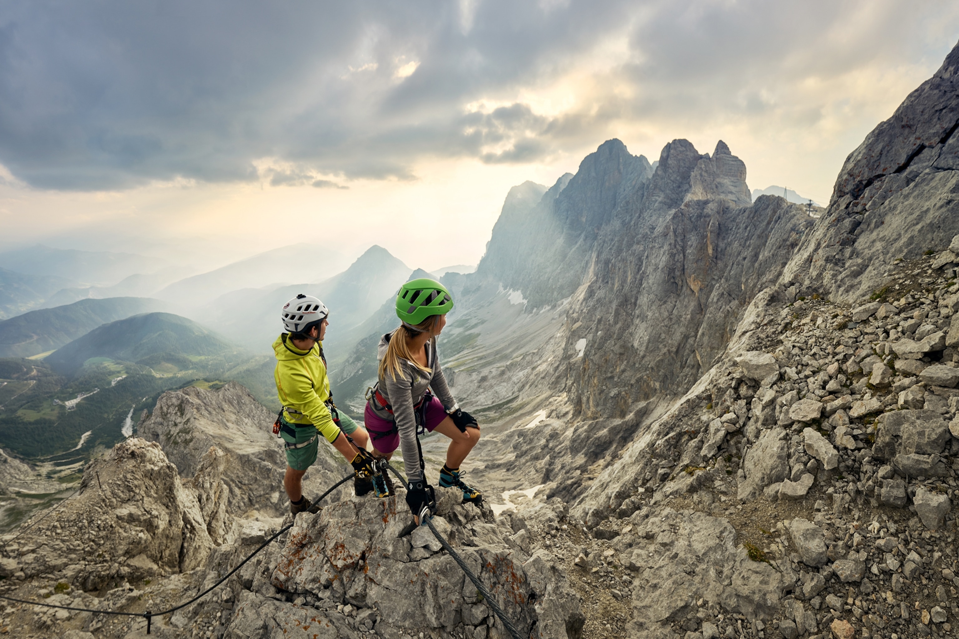 Two climbers look towards a mountain view.