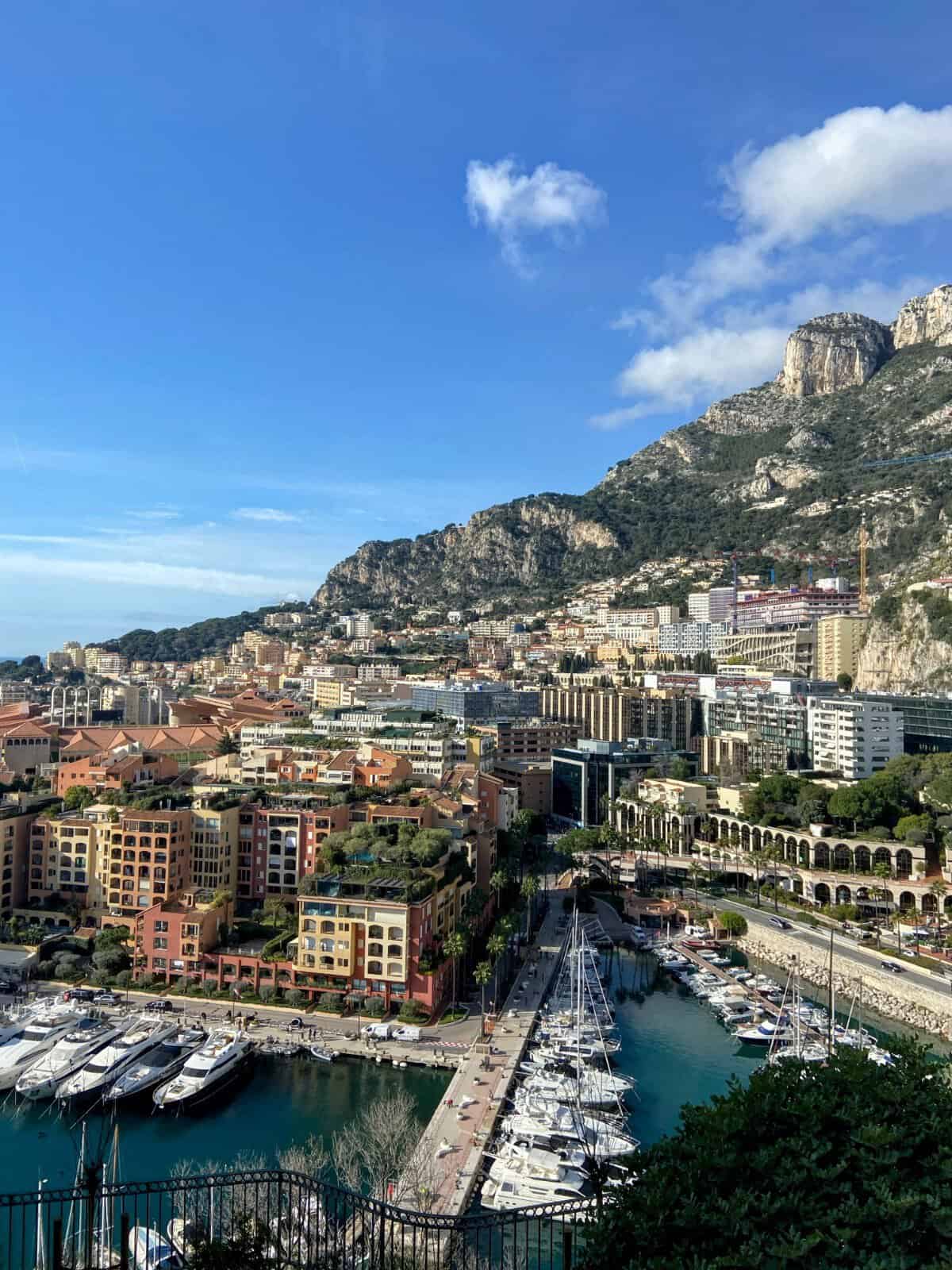 Hilltop view of Monaco with colourful houses along the hill and yachts in the marina below