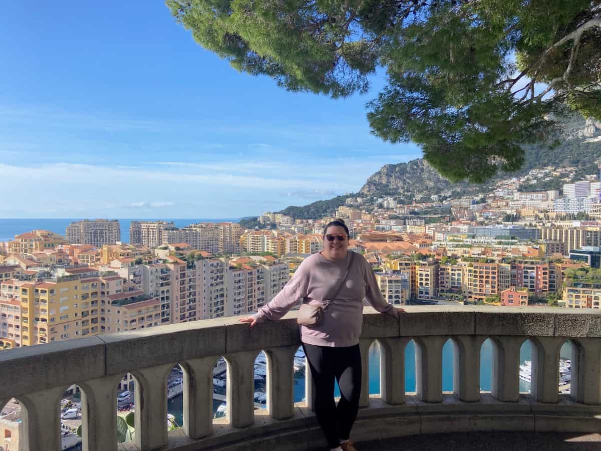 Riana standing along a balcony in Monaco overlooking the view after taking the train from Nice to Monaco for a day trip