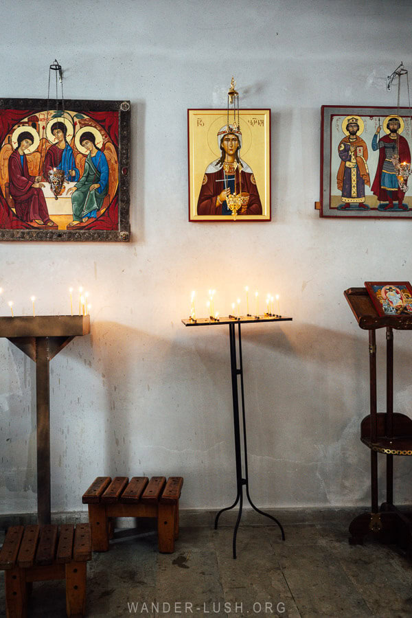 Icons hang on a white wall inside a monastery church of the shore of Lake Paravani in Georgia.