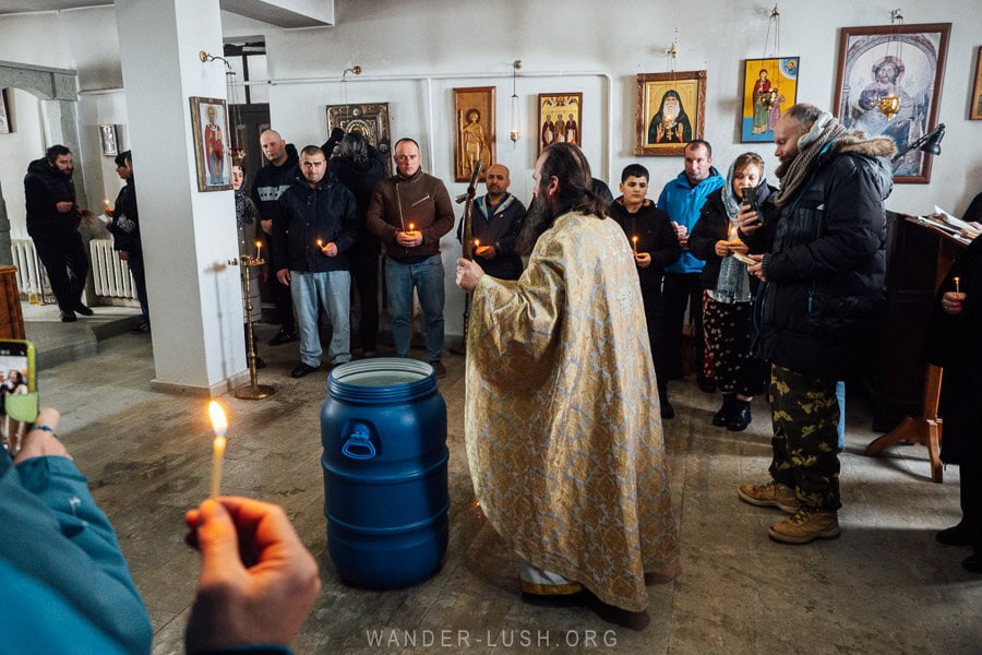 A priest dressed in golden robes blesses a blue barrel of water on Epiphany day in a small church in southern Georgia.