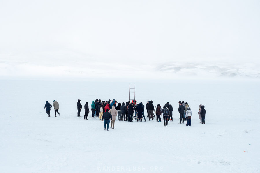 A crowd of people dressed in winter gear gathered on the frozen Lake Paravani in Georgia on Orthodox Epiphany.