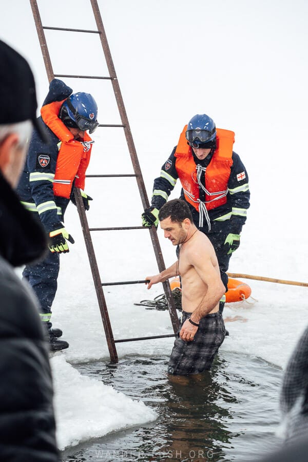 A man descends a ladder into the freezing waters of Paravani Lake as part of a Orthodox ritual for Epiphany.