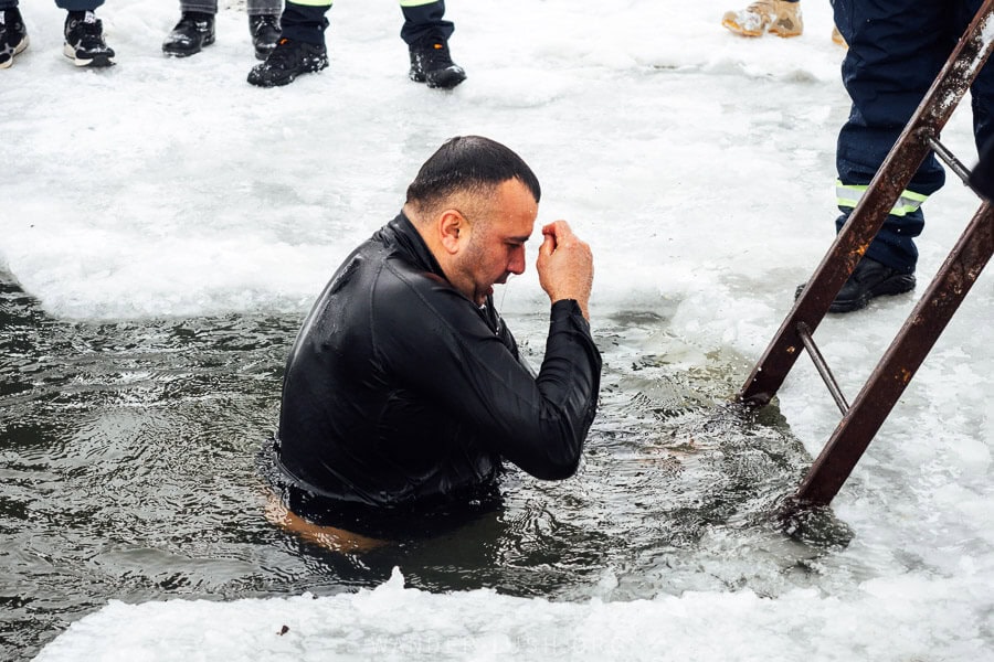 A man signs himself whilst standing waist deep in freezing water as part of an Epiphany ritual in Georgia.