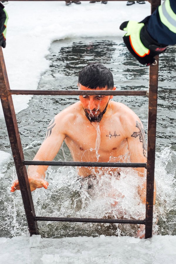 A man climbs out of the freezing lake water after plunging himself for Epiphany.