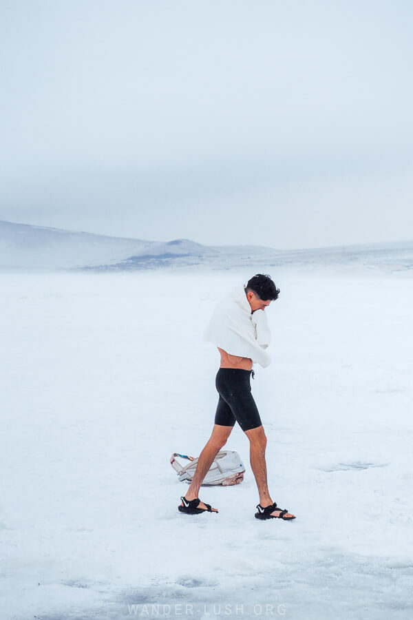 A man wrapped in a white towel walks across the surface of the frozen Paravani Lake after an ice plunge for Epiphany.