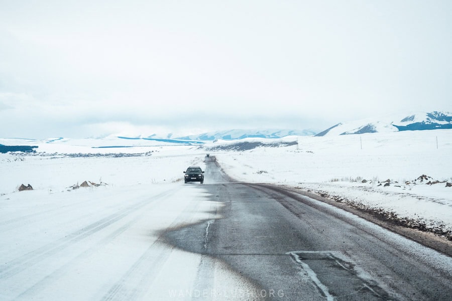 The Javakheti Plateau in winter, a car driving across a partially frozen road in Georgia.