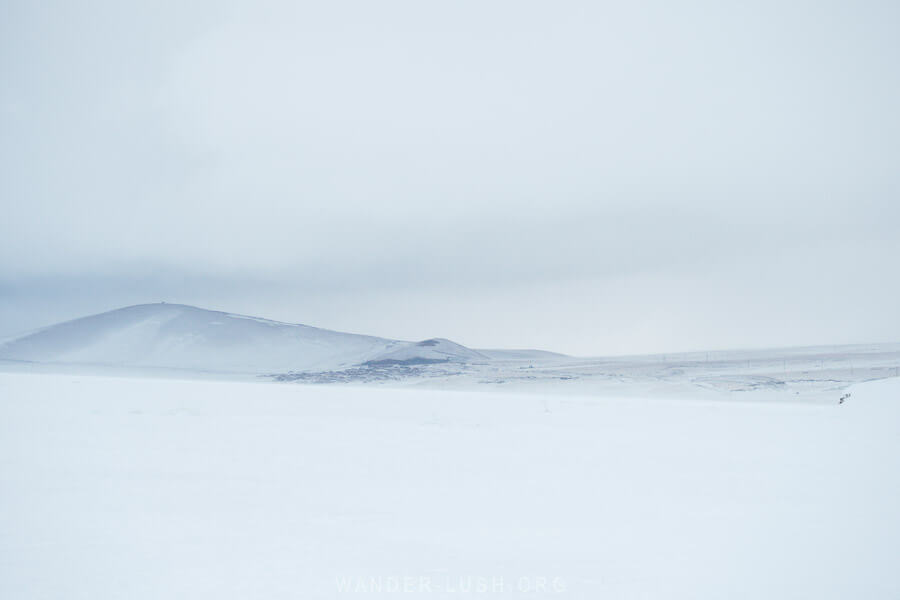 A frozen lake with volcanic mountains in the distance in the Javakheti Protected Areas, Georgia.