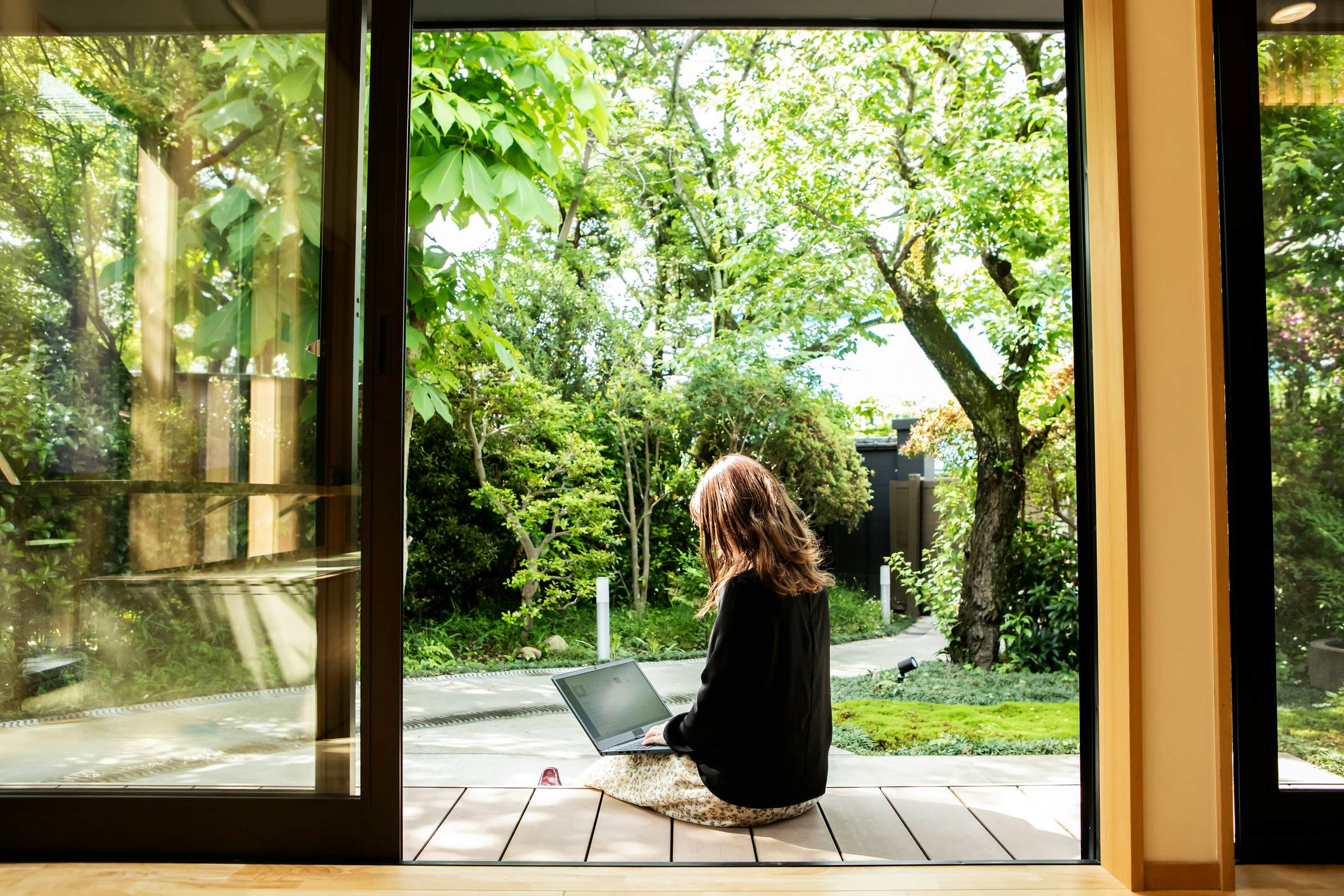 A woman working on her laptop outside a guesthouse in Japan